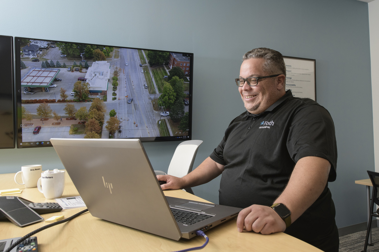 Man looking at computer with scan of city street on TV