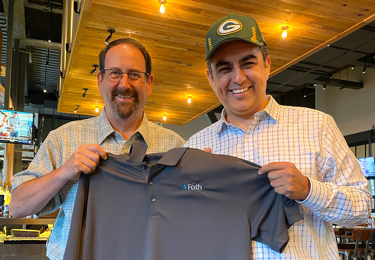 New member wears Green Bay Packers hat and holds up Foth shirt