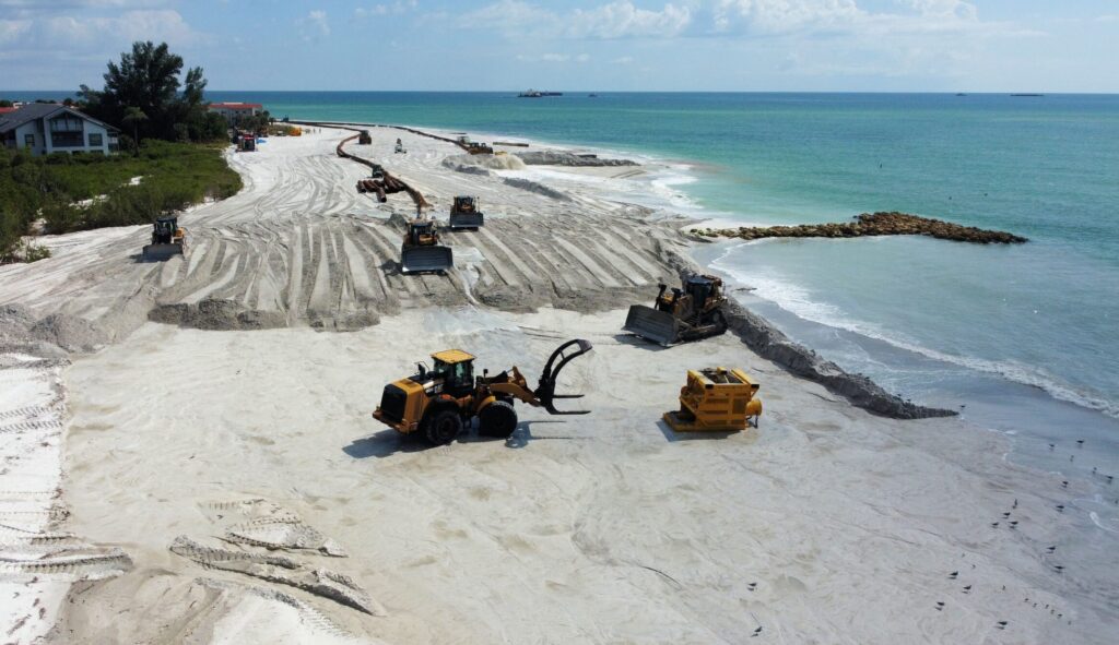 Construction equipment working on coastal infrastructure project on a beach