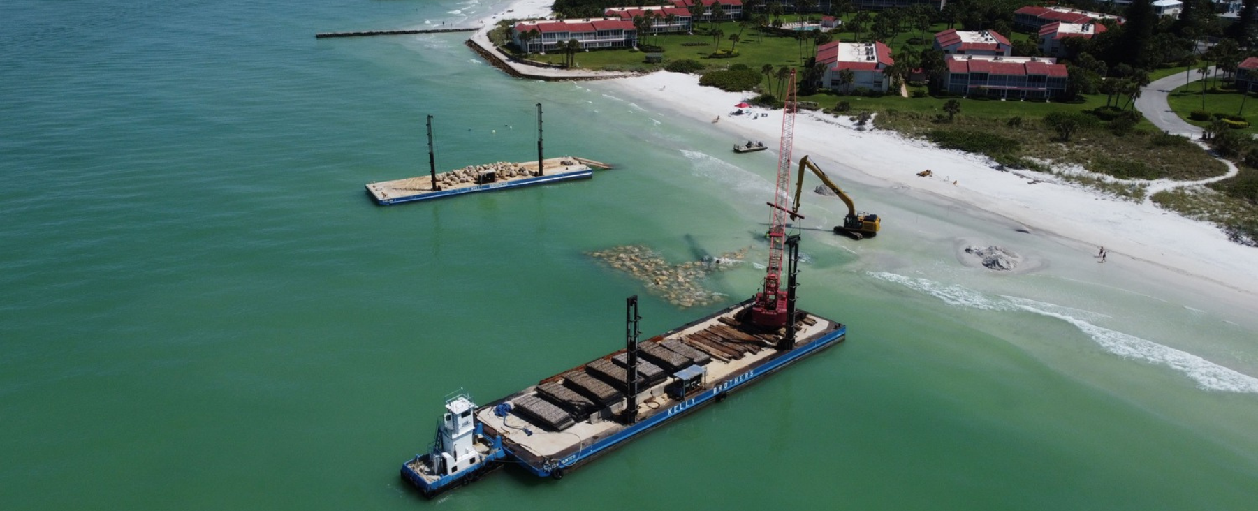 Aerial view of a beach and shoreline with visible construction activity.