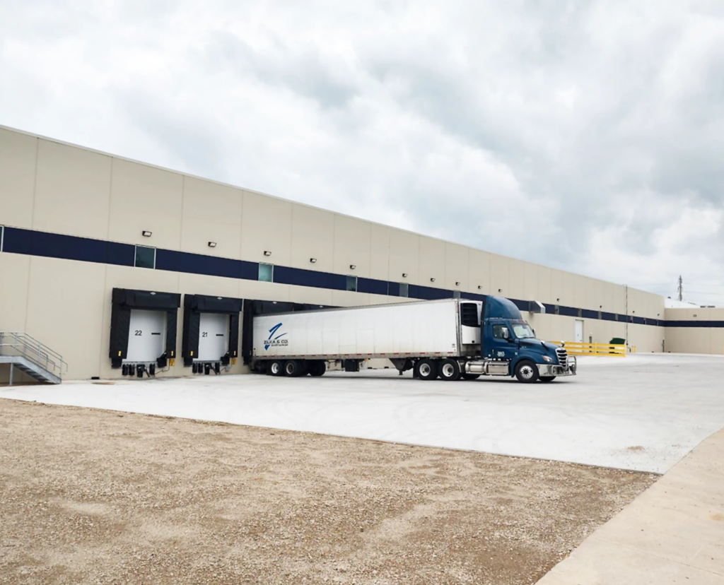 Expanded finished goods warehouse with truck at loading docks, supporting improved inventory control and efficient product distribution.